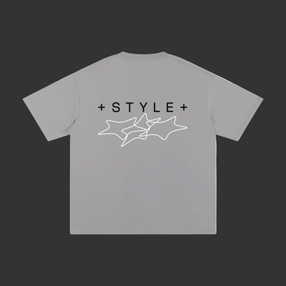 A light gray short-sleeve t-shirt shown from the back, featuring a black '+STYLE+' text graphic and a white line art star design printed on the center.